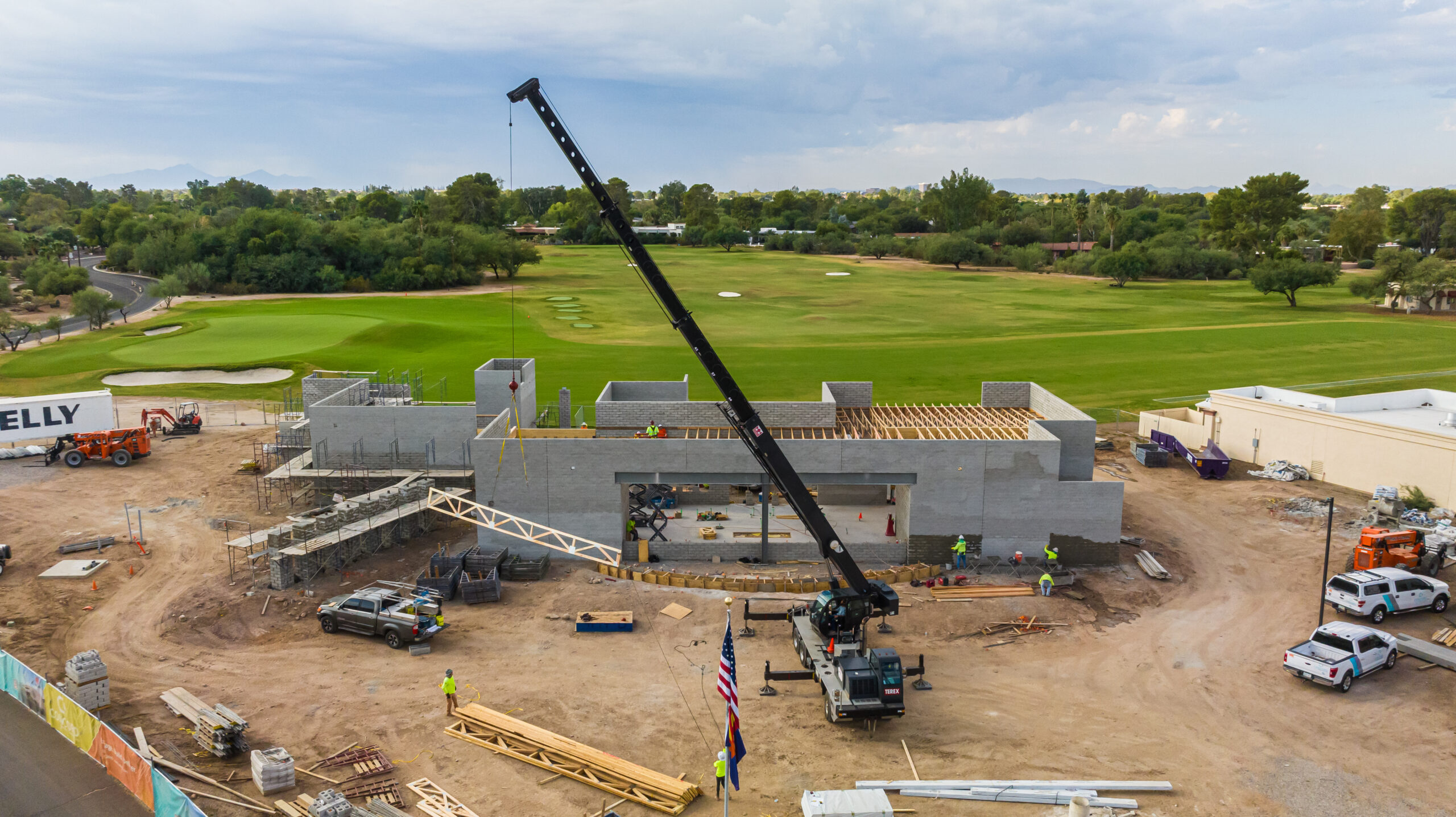 a construction drone photo showing the UA Clements Golf Facility under construction with a big crane in front and the golf course in the back
