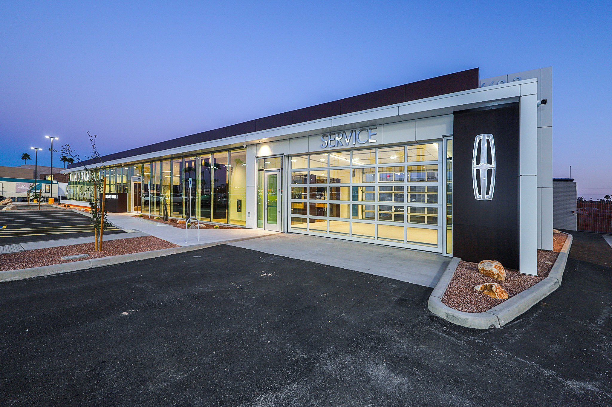 Exterior of car dealership with window paneled wall and Lincoln branded sign