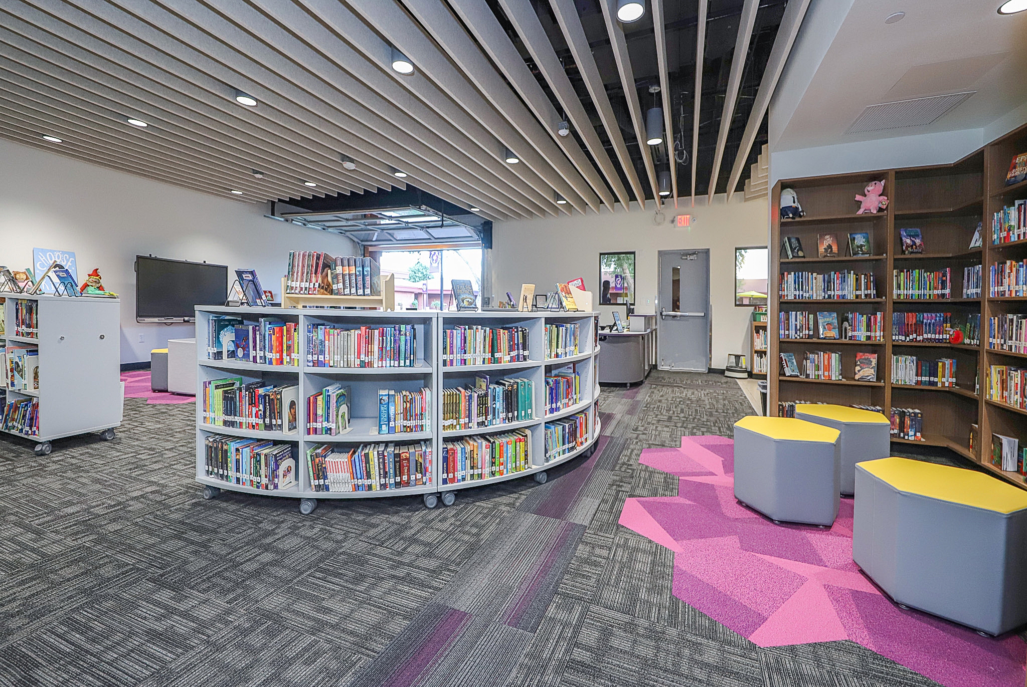 Elementary school library and media center with book-filled shelves and yellow stools.