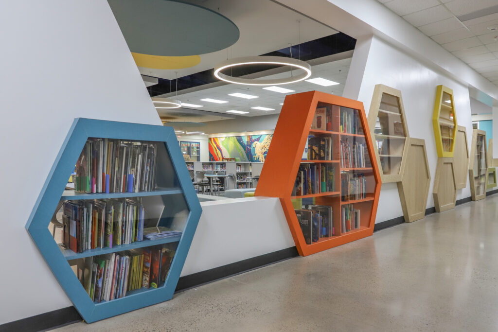Interior of K-12 library with books in multicolored shelving.