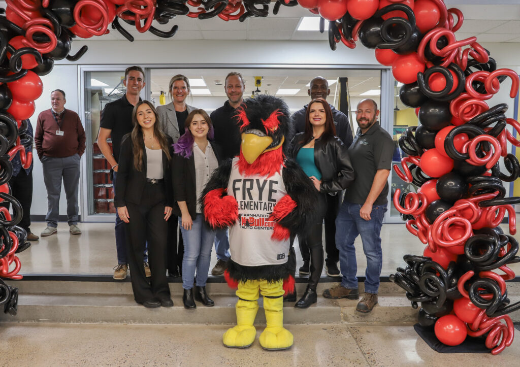 Concord staff posing with Frye Falcon mascot under balloon arch