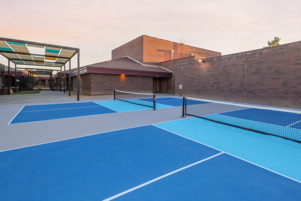Blue pickleball courts with student amphitheater in the background.