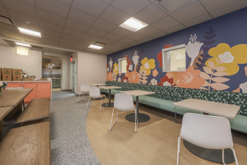 Interior dining area with tables, chairs, and a floral painted accent wall