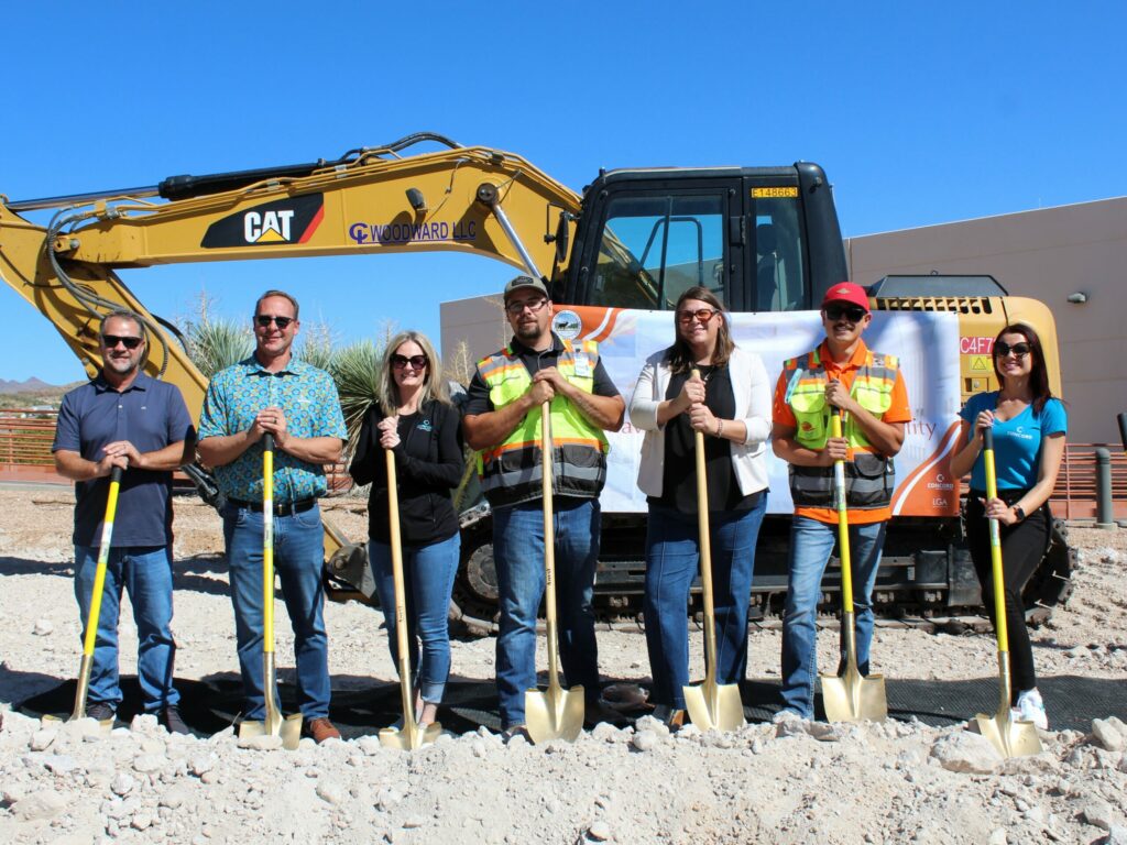 Concord Employee Owners holdings shovels in front of a tractor at a site