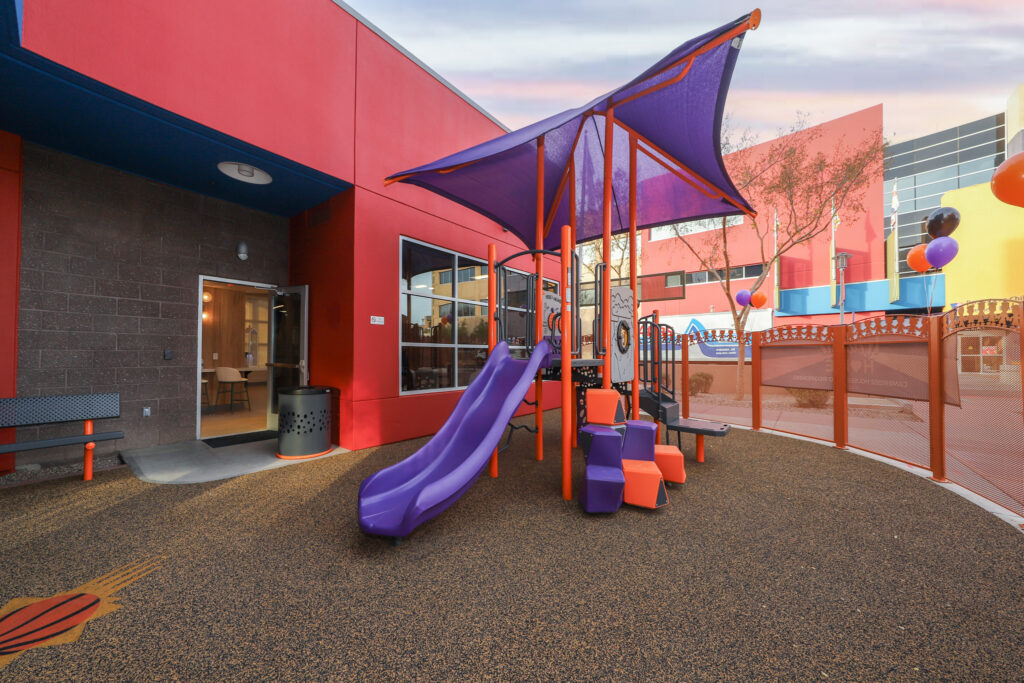 Outdoor Playground with purple slide and shade structure with red attachments