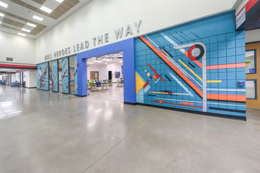 Interior of a hallway in an elementary school with a brightly painted mural on the wall.