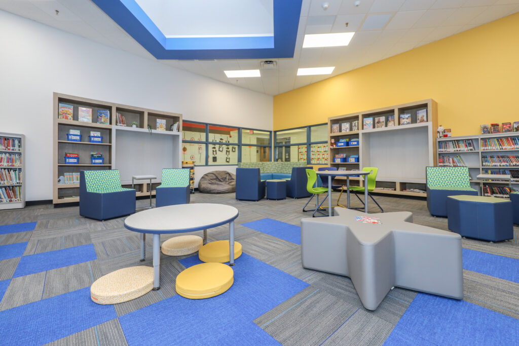 Interior of K-12 media center with colored seating and a star-shaped table.
