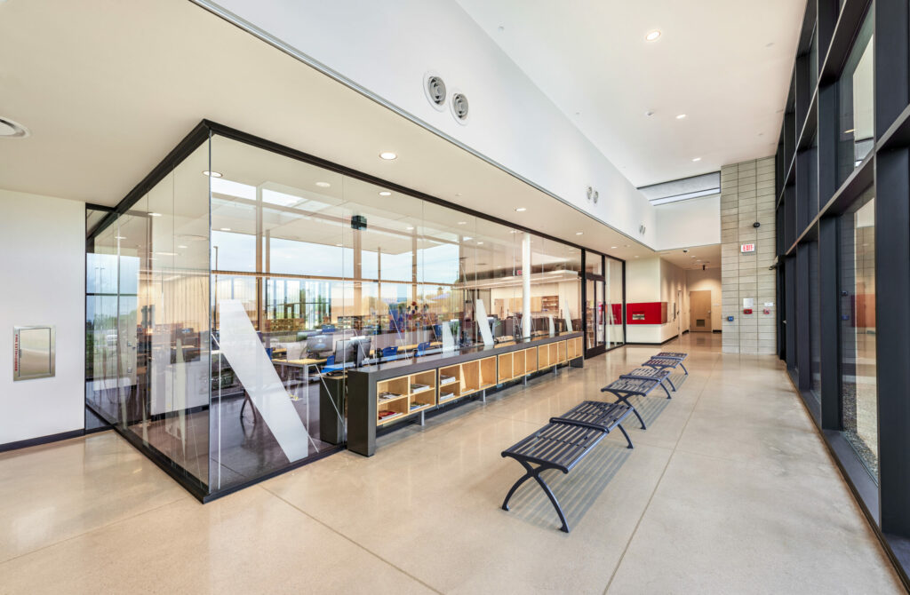 hallway with benches and a meeting room with glass walls